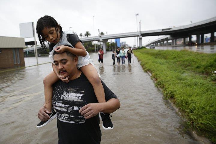 Jesus Nunez carries his daughter Genesis, 6, as he and his family flee their flooded home in Houston, TX on Aug. 27, 2017 