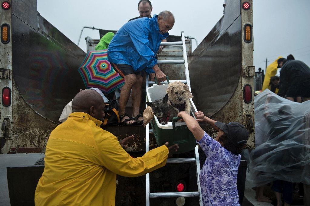 Evacuees are loaded onto a truck on an interstate highway overpass in the aftermath of Hurricane Harvey