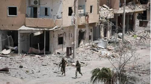 Fighters from Syrian Democratic Force (SDF) walk past damaged buildings in Raqqa city, Syria July 28, 2017.