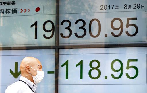 A man walks past an electronic stock indicator of a securities firm in Tokyo, Tuesday, Aug. 29, 2017.
