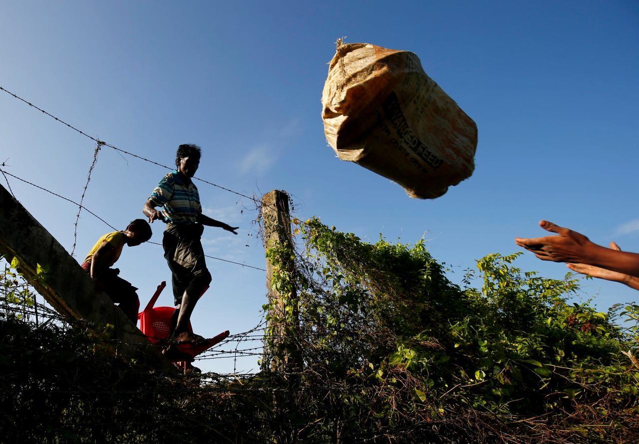  Rohingya people pass their belongings over the Bangladesh-Myanmar border fence