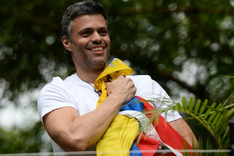 Venezuelan opposition leader Leopoldo Lopez holds a Venezuelan national flag against his chest, as he greets supporters gathering outside his house