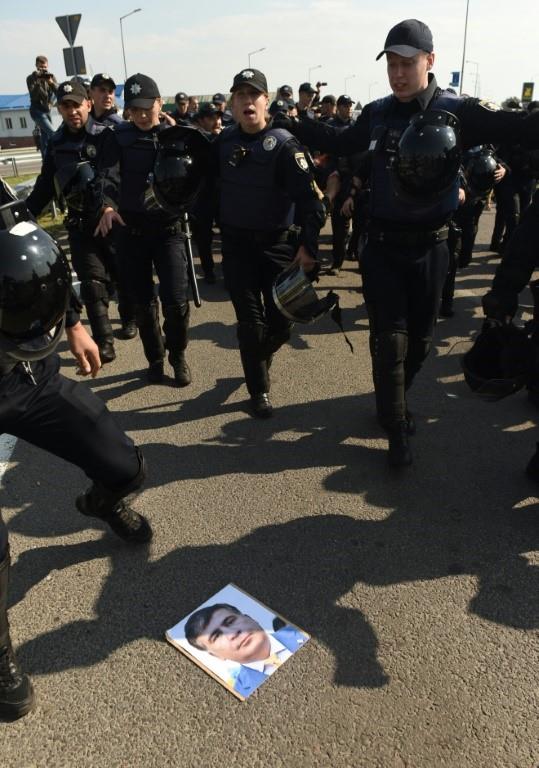 Ukrainian police restrain supporters of former Georgian president Mikhail Saakashvili (poster on the ground) at the Ukraine-Poland border who see the charismatic leader as someone who could fight corruption. 
