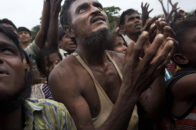  A Rohingya man stretches his arms out for food distributed by local volunteers, with bags