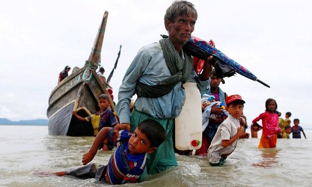 A Rohingya refugee pulls a child as they walk to shore after crossing the Bangladesh-Myanmar border by boat on Sunday.