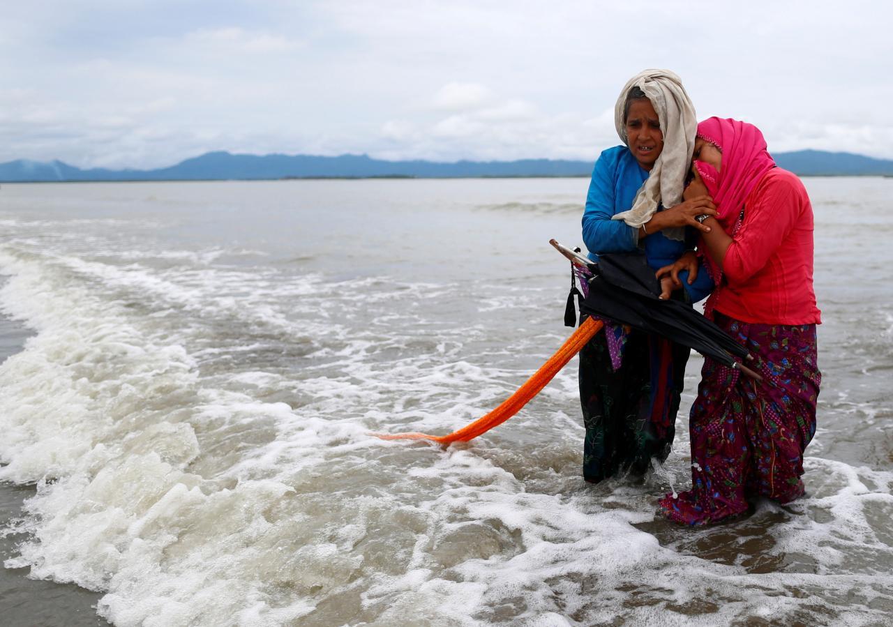  Rohingya refugee women cry as they walk to the shore after crossing the Bangladesh-Myanmar border by boat through the Bay of Bengal in Shah Porir Dwip, Bangladesh, 