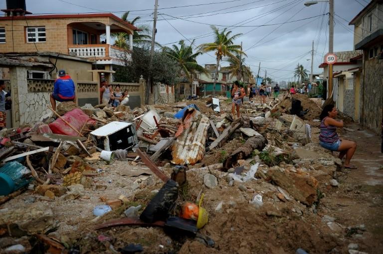 Residents sit on rubble in the Cojimar neighborhood of Havana following Hurricane Irma
