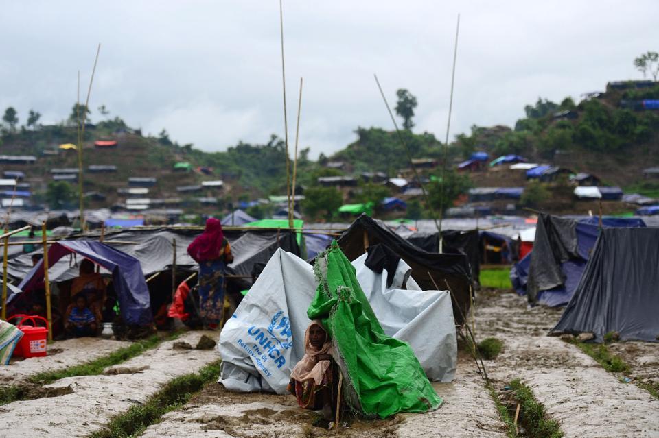 A Rohingya refugee woman sits next to a newly built makeshift shelter in a camp in the Bangladeshi locality of Ukhia on September 9, 2017.