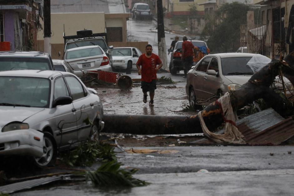 A man runs on the street next to debris and damaged cars after the area was hit by Hurricane Maria in Guayama, Puerto Rico September 20, 2017