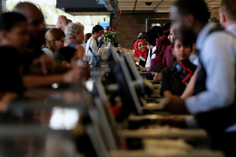 Airlines workers check passengers in for flights at the ticket counter at Dulles International Airport in Dulles, Virginia, U.S. 