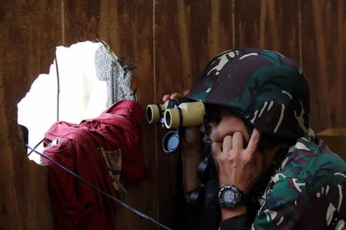 A Filipino soldier uses binoculars at his combat as government troops continue their