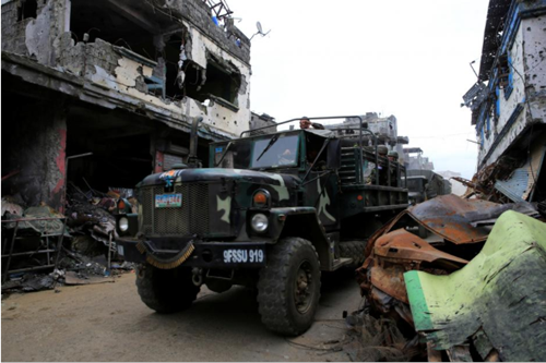 Government military trucks pass by damaged building and houses in Sultan Omar Dianalan boulevard at Mapandi district in Marawi city, southern Philippines September 13, 2017. 
