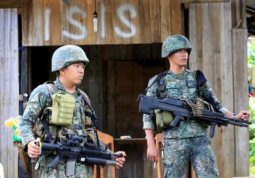 Soldiers stand guard along the main street of Mapandi village as government troops continue their assault on insurgents from the Maute group