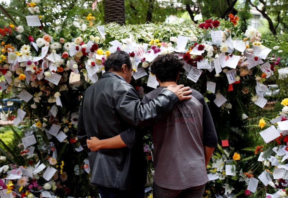 People hold each other while looking at flowers and little notes left for victims of an earthquake, in Mexico City, Mexico September 24, 2017.