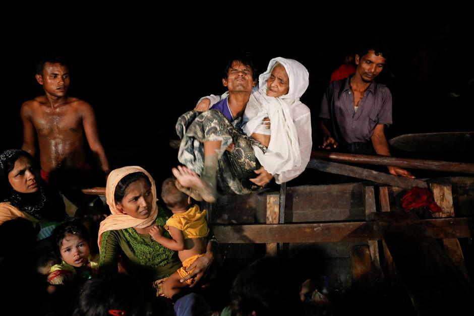 A man lifts an elderly woman from the boat as hundreds of Rohingya refugees arrive under the cover of darkness from Myanmar to the shore of Shah Porir Dwip, in Teknaf, near Cox's Bazar in Bangladesh, September 27, 2017