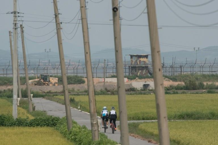  Cyclists pass before a South Korean military guard post before the skyline of North Korea (top) and the barbed-wire fence of the Demilitarized Zone (DMZ) separating the two countries, on Ganghwa island on Monday