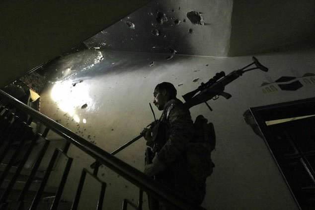 A Syrian Democratic Forces fighter patrols inside a building close to the Old City of Raqa on September 3, 2017 during the battle to seize the city from the Islamic State group