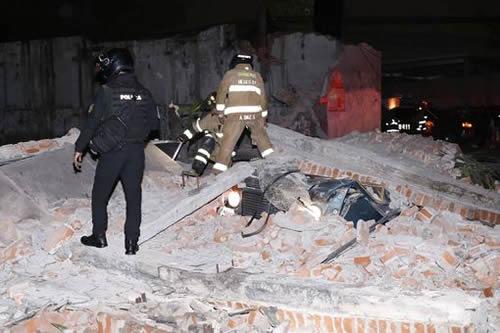 Rescuers stand amongst the rubble of a building