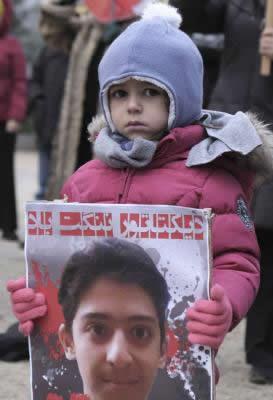 A little girl poses with portrait of Armin Sadeghi, 13, killed during demonstrations in Iran, as the Iranian community in Belgium gather in front of EU institutions headquarters, in Brussels on Wednesday