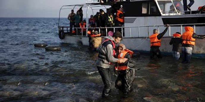  'A Syrian refugee helps a woman to leave a boat, after arriving on the Greek island of Lesbos'