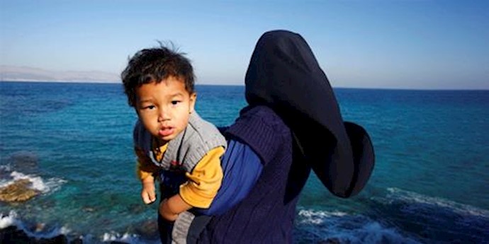  'A refugee woman holds her baby on a beach in the Turkish coastal town of Cesme'