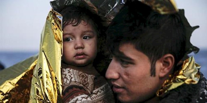  'An Afghan refugee and his baby are covered with a thermal blanket, moments after arriving on a raft on the Greek island of Lesbos'