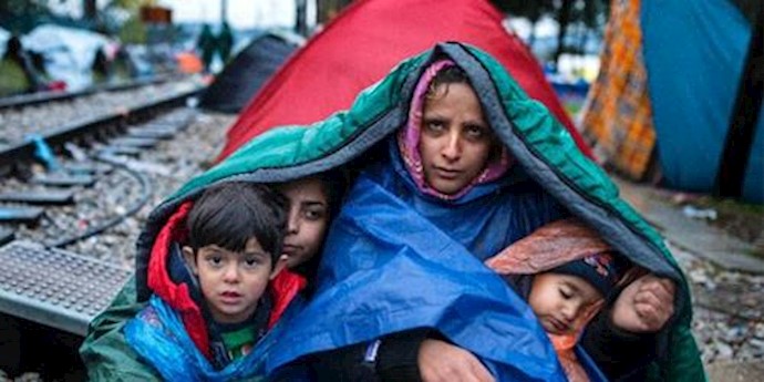  'A woman and her children look on as migrants and refugees wait to cross the Greece-Macedonia border in the rain on November 27, 2015 '