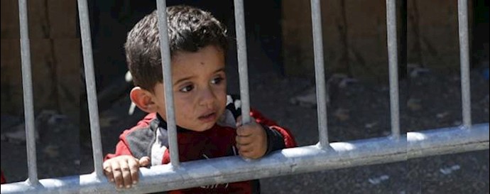  'A migrant boy looks through fence in a migrant processing center in the southern Serbian town of Presevo'