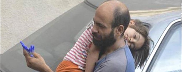  'Abdul, a Syrian refugee, selling pens on the streets of Beirut as he cradled his sleeping daughter'