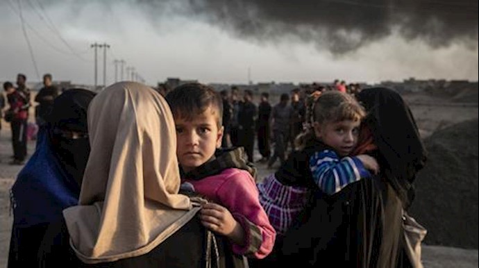  'Families displaced by fighting in the village of Shora gather at an army checkpoint on the outskirts of Qayyarah'
