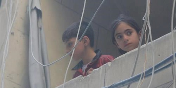  'Children look out from a balcony at a site hit by airstrikes, in the rebel-held area of Aleppos Bustan al-Qasr'