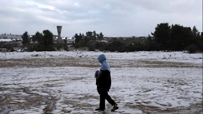  'A refugee carries clothes that were hung to dry during snowfall at a refugee camp in Ritsona, northern of Athens, Greece'