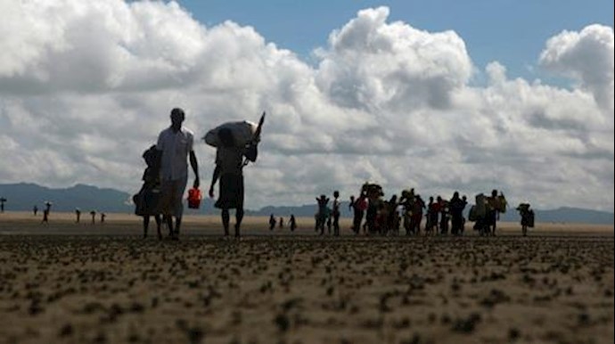  'Rohingya Muslim refugees walk on the Bangladeshi shoreline of the Naf river after crossing the border from Myanmar on the weekend'