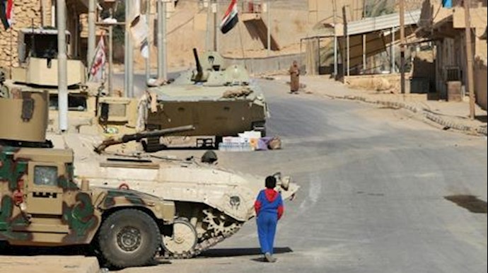 'A boy walks past Iraqi forces vehicles in Rawa on November 18, 2017, after troops retook the Euphrates valley town from Islamic State group jihadists'