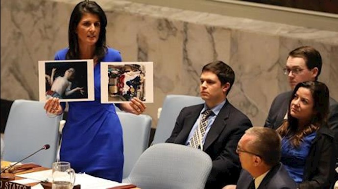  'US Ambassador to the UN Nikki Haley holds photographs of victims during a Security Council meeting on Syria on April 5, 2017'