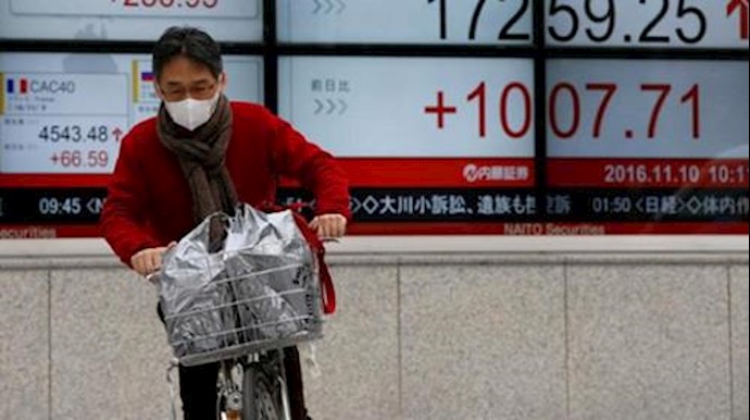  'A man cycles in front of electronic boards showing Japans Nikkei average (R) and the Dow Jones average (L top) outside a brokerage in Tokyo'