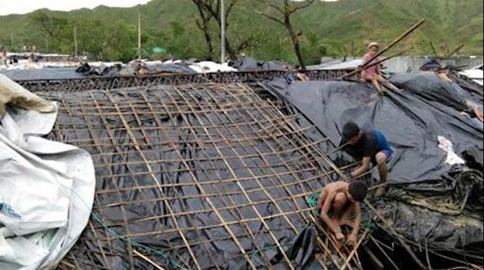  'Rohingya refugee children fix the damaged roof of a hut in a makeshift camp in Bangladeshs Coxs Bazar district on May 30, 2017'