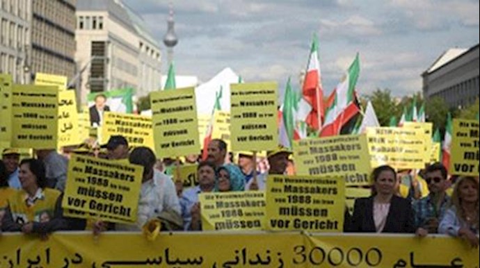  'Banners in German read ‘The people who are responsible for the 1988 massacres in Iran need to be brought to justice'