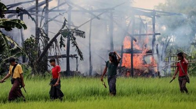  'Armed men passing a burning house on 7 September 2017 in the Burmese state of Rakhine, where many Rohingya live.'